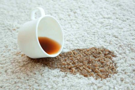 A cup of coffee sitting on the floor next to a carpet.